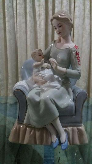 Porcelana madre en sofá cargando a su bebe.