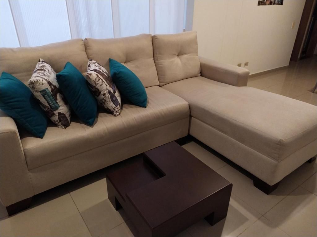 Sofa en L color beige mesa de centro y cojines decorativos